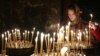 FILE - A woman lights a candle during a religious service at a church in Kyiv, February 23, 2014. 
