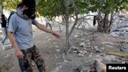 Seorang aktivis memakai masker gas, menunjuk pada seekor anjing yang mati saat ia mencari jenazah warga untuk memeriksa adanya penggunaan senjata kimia di Zamalka, Damaskus (22/8).