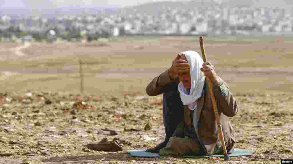 A Kurdish refugee man reacts as smoke rises from the Syrian town of Kobani as seen from the Mursitpinar crossing on the Turkish-Syrian border, Oct. 26, 2014. 