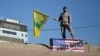 An Iranian guard holds a Hezbollah flag during a funeral procession and burial for Iranian Major-General Qassem Soleimani, in Kerman, Iran, Jan. 7, 2020. 