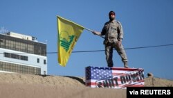 An Iranian guard holds a Hezbollah flag during a funeral procession and burial for Iranian Major-General Qassem Soleimani, in Kerman, Iran, Jan. 7, 2020. 