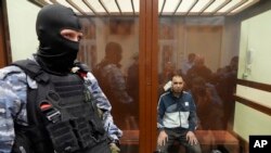 모스크바 공연장 테러 용의자 가운데 한 명인 사이다크라미 라차발리조다(오른쪽)가 24일 시내 법원에 출두하고 있다. 얼굴이 부었고 귀에 붕대를 부착했다.