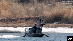 FILE - North Korean fishermen work from their boat in the Yalu River, as seen from Dandong in northeastern China's Liaoning Province, Tuesday, Feb. 9, 2016.