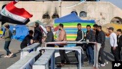Para pemrotes melewati pos pemeriksaan setibanya di lapangan Tahrir, saat berlangsungnya aksi unjuk rasa di Baghdad, Irak, 25 Desember 2019. (AP Photo/Nasser Nasser)