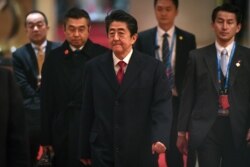 Japan's Prime Minister Shinzo Abe, center, leaves after a bilateral meeting with South Korean President Moon Jae-in, at hotel on the sidelines of the trilateral leaders' meeting between China, South Korea and Japan in China.