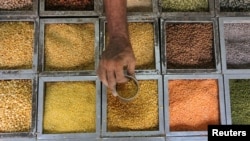 Seorang pekerja mengumpulkan biji-bijian lentil dari sebuah wadah di toko bahan pangan di Mumbai, India. (Foto:Dok)