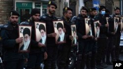 Sejumlah petugas kepolisian Iran menunjukkan poster Pemimpin Tertinggi Iran Ayatollah Ali Khamenei saat melindung Kedutaan Besar Prancis saat demo memprotes karikatur Ali Khamenei oleh majalah Prancis Charlie Hebdo, di Teheran, Iran, 8 Januari 2023. (Foto: Vahid Salem/AP Photo)