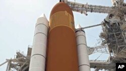 The STS-134 crew stands together on Launch Pad 39A in front of the towering external fuel tank and solid rocket boosters of space shuttle Endeavour, one day before its final flight, April 28 2011
