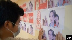 An anti-coup protester looks at the images of ousted Myanmar leader Aung San Suu Kyi during a protest against the military coup in Yangon, April 26, 2021.