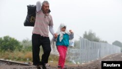 Migrants walk along a railway track as they cross the Hungarian border with Serbia near a collection point in Roszke, Hungary, Sept. 11, 2015.