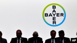 Anggota dewan pengawas duduk di depan logo perusahaan selama pertemuan pemegang saham tahunan dari perusahaan kimia Jerman Bayer AG di Bonn, Jerman, 25 Mei 2018. (Foto: dok).