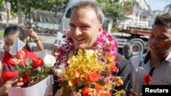 Aktivis hak buruh Inggris, Andy Hall (tengah) menerima rangkaian bunga dari para pendukungnya setibanya di Pengadilan Provinsi Phra Khanong di Bangkok, 29 Oktober 2014. (Foto: dok).