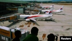 FILE - Children look at Malaysia Airlines Boeing 737-800 aircrafts parked at Kuala Lumpur International Airport.