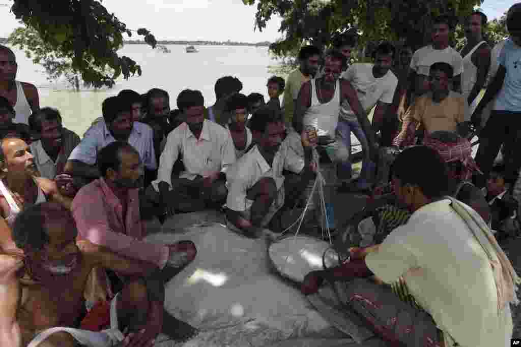 Flood affected villagers receive rice being distributed as relief by the government at Gagalmari village in Assam state, India, July 2, 2012.