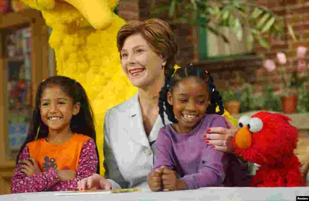 U.S. first Lady Laura Bush (center) poses with Sydney Martinez (left) Sienna Jefferies (right) and Sesame Street character, Elmo, after reading a book to the children, New York, Sept. 19, 2002.