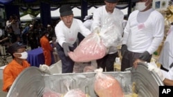 Pegawai Departemen Kesehatan Publik Thailand melempar metamfetamin hasil sitaan ke keranjang sebelum membakarnya. (Foto: Dok)