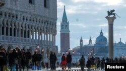 People walk through across a makeshift walkway over the flooded St. Mark's Square in Venice, Italy.