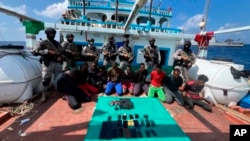 This photograph provided by the Indian Navy shows armed naval commandos standing behind 10 captured Somali pirates with their hands tied behind after they thwarted a piracy attempt on the Iranian-flagged fishing vessel Al Naeemi off the east coast of Somalia, Jan.29, 2024.
