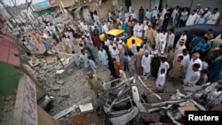 Warga Karachi berkumpul dekat kendaraan-kendaraan yang rusak akibat ledakan bom di kantor Partai Nasional Awami (ANP), Sabtu (27/4).