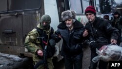 An elderly Ukrainian man is helped by an Ukrainian army soldier and a citizen during a evacuation of civilians in Debaltseve, in the Donetsk region, Feb. 3, 2015.