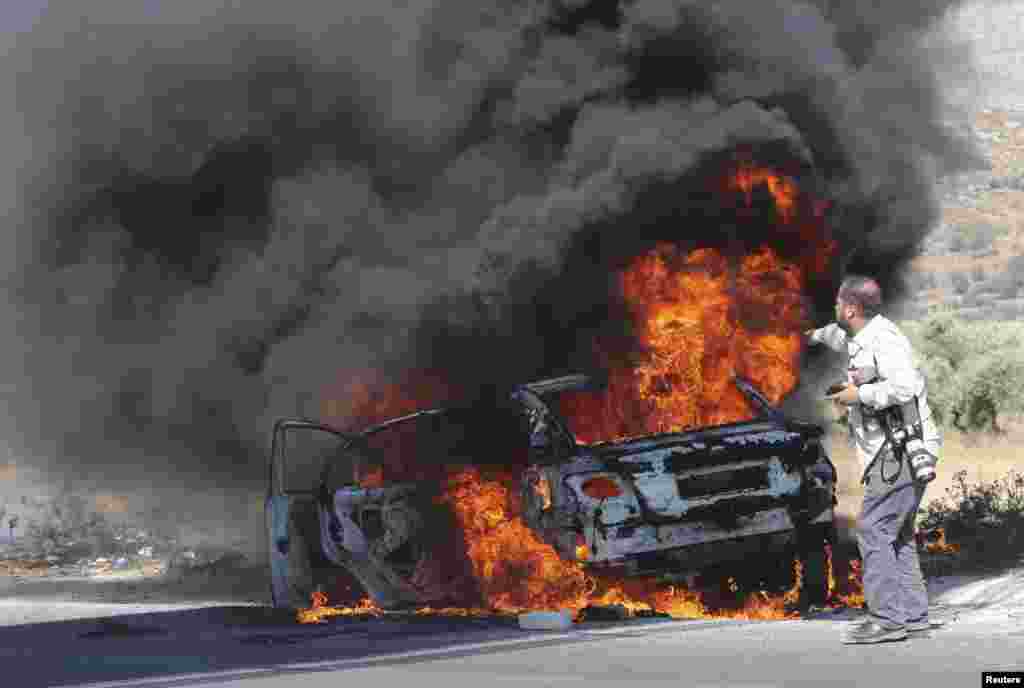 AFP photographer Jaafar Ishtayeh looks at his burning car after it was hit by tear gas canisters fired by Israeli soldiers, during a protest by Palestinians against Israeli air strikes in Gaza strip, at Hawara checkpoint near the West Bank city of Nablus.