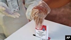 Seorang perempuan yang mengenakan sarung tangan plastik memberikan suaranya saat pemilihan kepala daerah di sebuah TPS di Tangerang, Rabu, 9 Desember 2020. (AP//Tatan Syuflana)