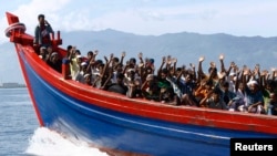 FILE - Ethnic Rohingya refugees from Myanmar wave as they are transported by a wooden boat to a temporary shelter in Krueng Raya in Aceh Besar, Indonesia, April 8, 2013.