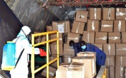 FILE - A member of a medical team wearing a protective suit sanitizes cargo inside a plane at the airfield, to prevent the spread of the coronavirus disease, at the Juba International Airport in Juba, South Sudan, April 5, 2020.