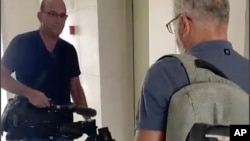 Seorang petugas Israel (kiri) tampak menyita peralatan video milik kantor berita AP dari blok apartemen di kota Sderot, Israel Selatan, hari Selasa, 21 Mei 2024.