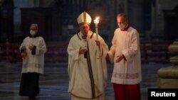 Pope Francis holds a candle as he arrives to celebrate a Mass to mark the World Day For Consecrated Life in St. Peter's Basilica at the Vatican, Feb. 2, 2021.