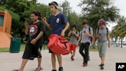 A group of Pokemon Go players check their smartphones as they look for Pokemon, Tuesday, July 12, 2016, at Bayfront Park in downtown Miami.