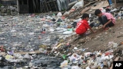 Dua anak Indonesia tengah bermain di dekat sungai yang penuh dengan onggokan sampah di salah satu sudut kota Jakarta (Foto: dok). 
