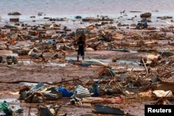 Dečak nosi deo srušenog krova na plaži na ostrvu Majot (Foto: Reuters/Gonzalo Fuentes)