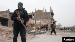 Afghan police officers are seen at the site of a car bomb attack in Herat province, west of Kabul, Afghanistan, March 13, 2021. 