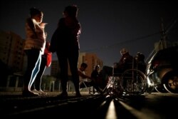 FILE - Patients with kidney disease and their relatives wait on the street for the return of electricity, in front of a dialysis center during a blackout, in Maracaibo, Venezuela, April 13, 2019.