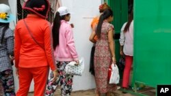 Cambodian garment workers return to a factory after their lunch break in Phnom Penh, Cambodia Thursday, March 12, 2015. 