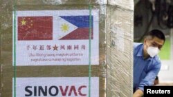 FILE - A worker unloads a box of Sinovac Biotech's CoronaVac vaccines from a Chinese military aircraft at Villamor Air Base in Pasay, Metro Manila, Philippines, Feb. 28, 2021.