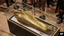 Journalists gather around the golden coffin that once held the mummy of Nedjemankh, a priest in the Ptolemaic Period some 2,000 years ago, at the National Museum of Egyptian Civilization, in Old Cairo, Egypt, Oct. 1, 2019.