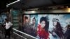 Orang-orang berdiri di dekat iklan yang mempromosikan film Disney "Mulan" di halte bus di Beijing, Cina, 9 September 2020. (Foto: REUTERS / Carlos Garcia Rawlins)