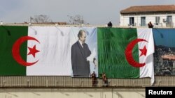 Des employés de la ville installe le drapeau algérien et un poster du président Abdelaziz Bouteflika, à Alger, en Algérie, le 26 avril 2016.