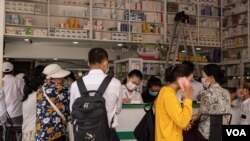 មនុស្ស​ម្នា​ពាក់ម៉ាស់​ទិញ​ថ្នាំ​នៅ​ឱសថស្ថានមួយ ក្នុង​រាជធានី​ភ្នំពេញ​ នៅពេល​ដែល​វីរុស​កូរ៉ូណាកំពុង​ផ្ទុះ​​ឡើ​ងទូទាំង​សាកលលោក ​ថ្ងៃទី​១៧ ខែមីនា ឆ្នាំ២០២០។ (ទុំ ម្លិះ/VOA)