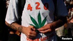 FILE - A man holds a joint during a gathering of marijuana advocates at Golden Gate Park in San Francisco, California.