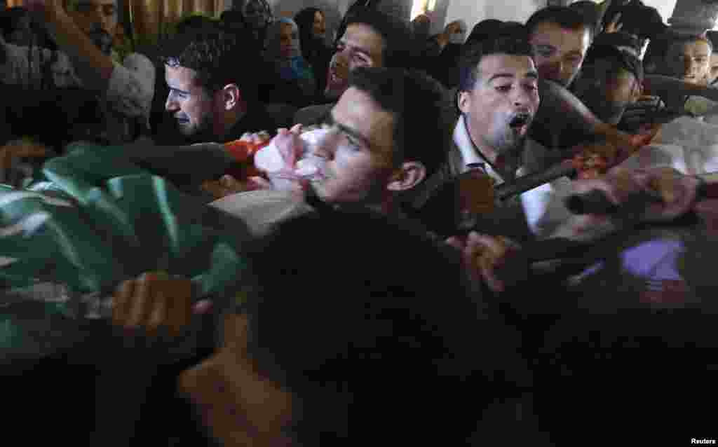 Mourners carry two bodies out of three Palestinian members of Abu Muamar family, who hospital officials said were killed in an Israeli air strike on their house, during their funeral in Rafah in the southern Gaza Strip July 14, 2014.