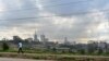 FILE - A section of Nairobi's city scape is seen May 16, 2019, through a crisscross of electrical lines as a man on his morning commute walks along Mbagathi Way in the Kenyan capital's southern sector.