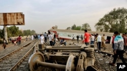 People gather at the site where a passenger train derailed injuring at least 100 people, near Banha, Qalyubia province, Egypt, April 18, 2021.