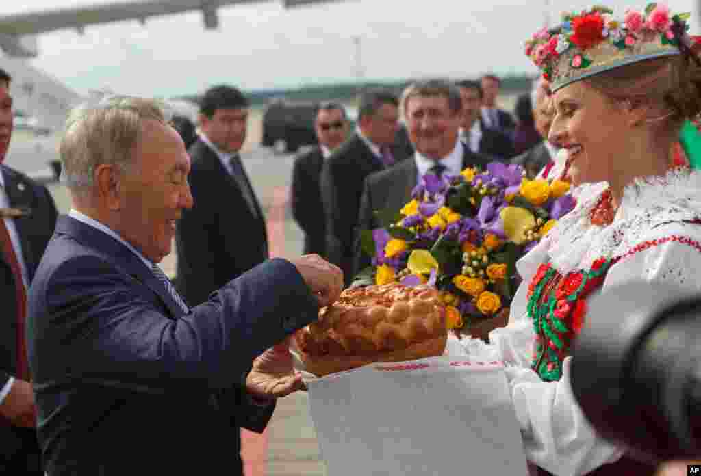 Kazakhstan's President Nursultan Nazarbayev, left, gets traditional salt and bread upon arrival in Minsk, Belarus, Aug. 26, 2014.