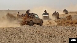 FILE - Fighters ride in pickup trucks as forces loyal to Yemen's Saudi-backed government clash with Houthi rebels in al-Jadaan, in Yemen's Marib governorate, Nov. 22, 2020.
