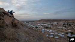 Des hommes sont assis au sommet d'une colline surplombant une partie du camp de réfugiés d'Umm Rakouba, accueillant des personnes qui ont fui le conflit dans la région du Tigray en Éthiopie, à Qadarif, dans l'est du Soudan, le 14 décembre 2020.