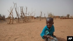 FILE - А boy is seen eating dry couscous in the village of Goudoude Diobe, in the Matam region of northeastern Senegal.
