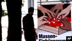 FILE - A man walks by a poster of the Swiss People's Party (SVP/UDC) argueing against the automatic right to citizenship, even for children born in Switzerland to foreign parents on Sept. 9, 2004.